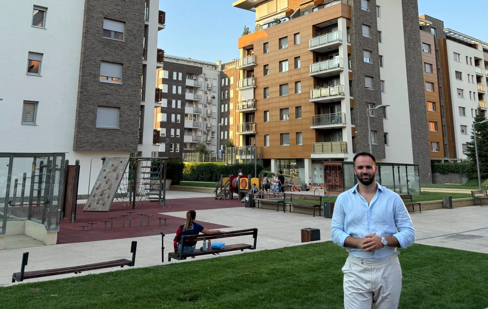 Moderni stambeni kompleks u Beogradu sa igralištem u dvorištu i ljudima u opuštenoj atmosferi.